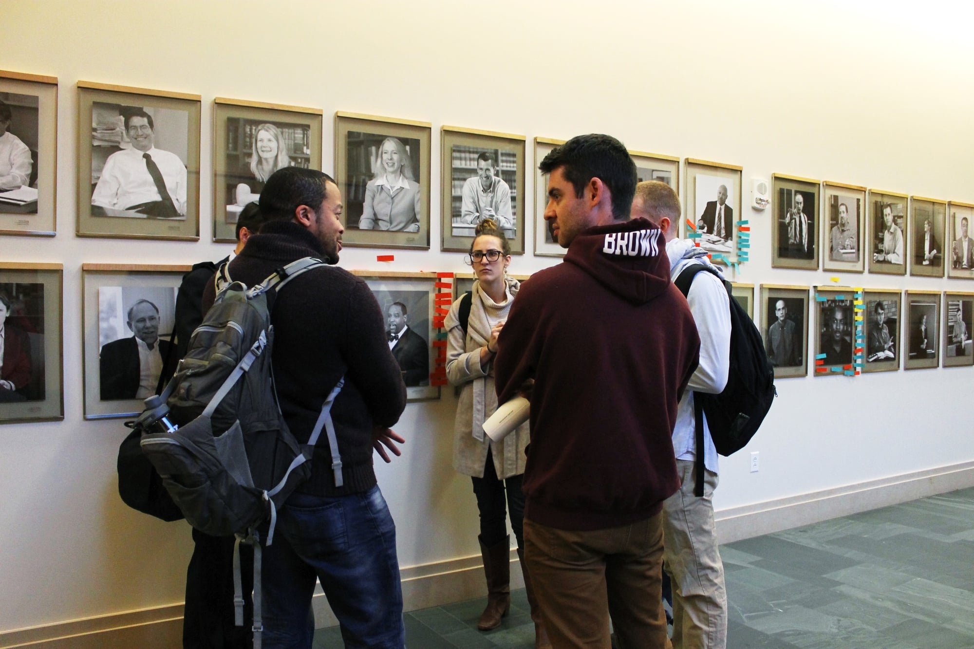 A group of Law School students discusses the vandalism on the portraits of black Law School professors in front of the portraits on the first floor of Wasserstein Hall in the afternoon.  