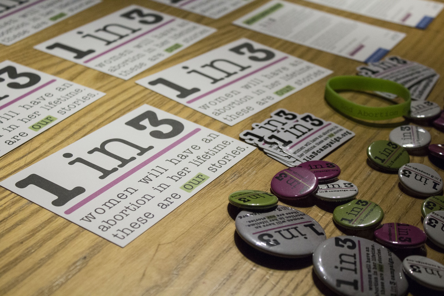 Buttons and stickers in support of the 1 in 3 Campaign cover the surface of a desk outside Fong Auditorium on Thursday night. The campaign, which cites a statistic that 1 in 3 women will have an abortion before age 45, shares the stories of people who have abortions to work towards ending the shame and stigma that women often feel about it. A dramatic reading called “Out of Silence” dedicated to performing a selection of those stories was organized by the Harvard College International Women’s Rights Collective. 