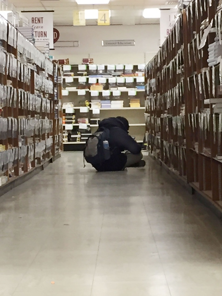 Computer Science concentrator Michael J. Woo ’16 reads a book in aisle 4 of the Harvard COOP bookstore, where many students purchase course books, on Wednesday afternoon.