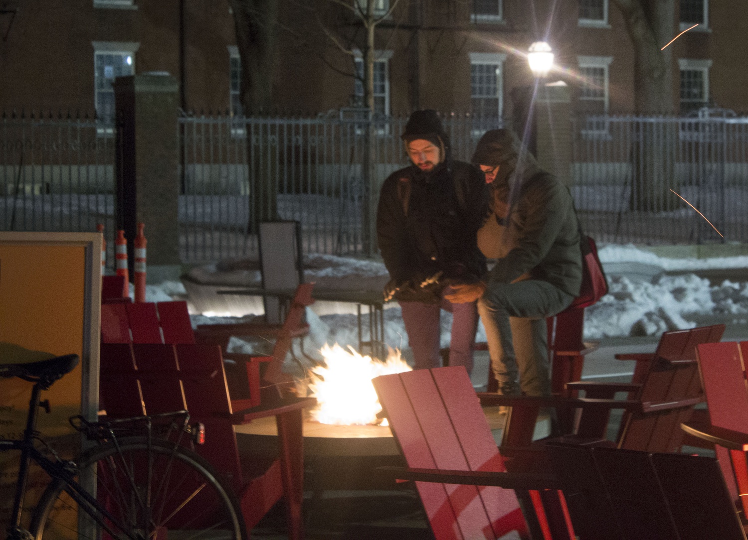 Carl Leahman and Leo Koch make a stop to warm up by the fire pits in Science Center Plaza. Locals bundled up to keep warm as temperatures dropped into the single digits in Cambridge Thursday night.
