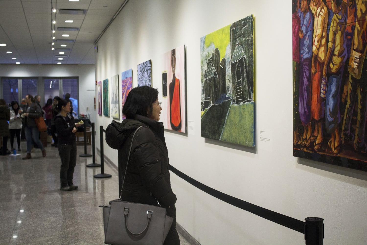 People eat hors d’oeuvres and view the work on display at the opening of “Altered State: Painting Myanmar in a Time of Transition.” The gallery, featuring paintings by Burmese artists, went up in CGIS South Concourse Thursday evening.
