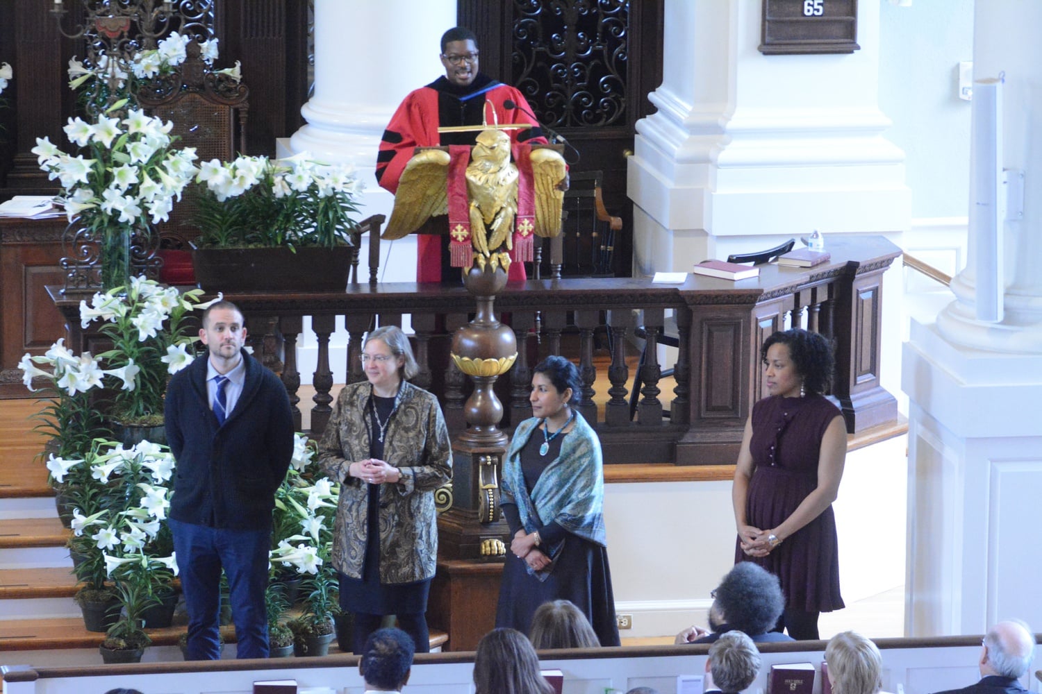 Professor Jonathan Walton delivers instructions on the taking of communion for attendees at the Easter service Sunday morning, as volunteers prepare to distribute wine and bread while attendees look on.