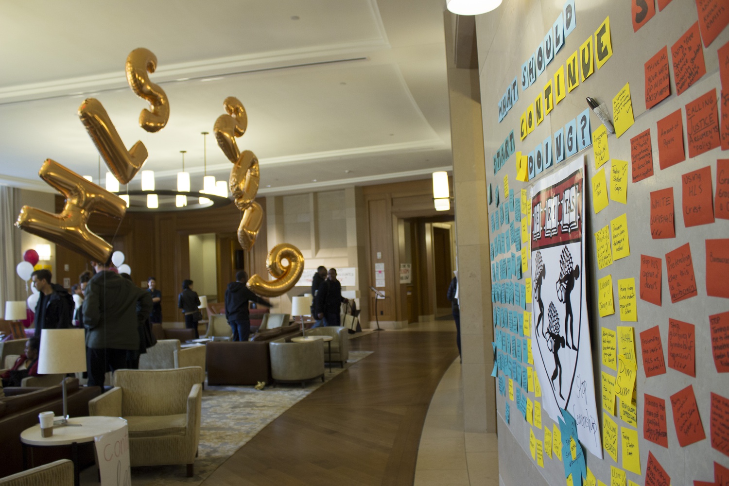 Students mingle in the Caspersen Student Center during Harvard Law School’s admitted students weekend. Signs welcoming the new students hung alongside those advocating for increased support for minorities at the Law School.