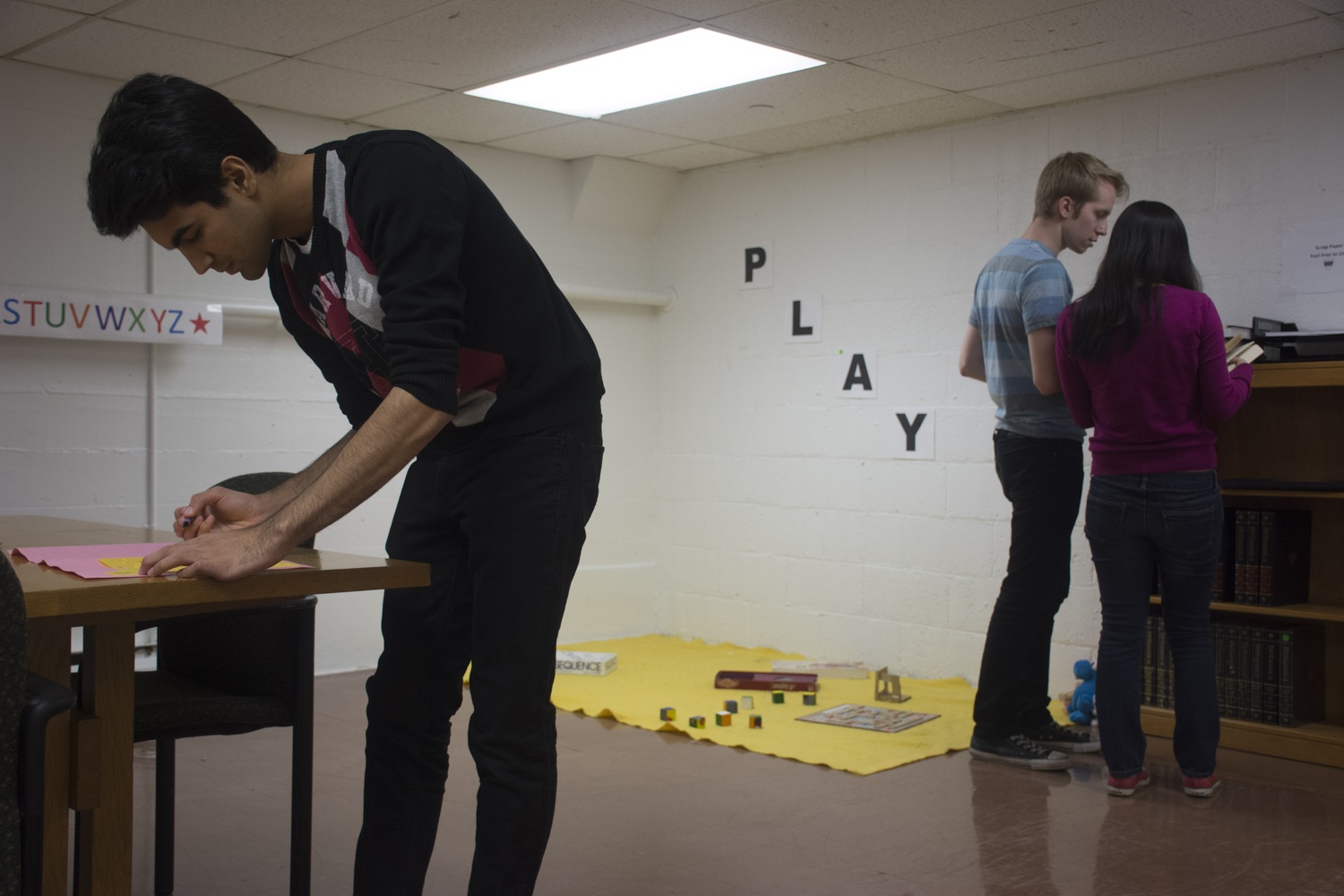 Saad Amer ‘16 (left) and two of his partners solve puzzles with clues during their one-hour Escape the Room challenge in Eliot basement.
