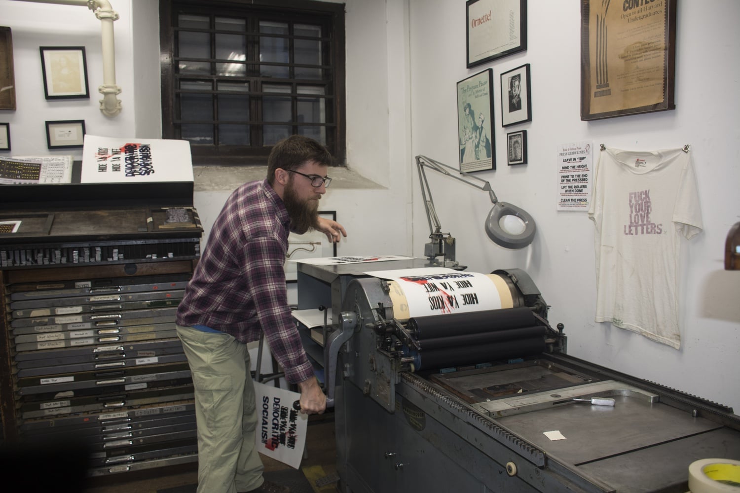 A man turns the press handle to print out a poster. The Bow & Arrow Press, located in the basement of Adams House B entryway, had a Open Press Night on Wednesday. 
