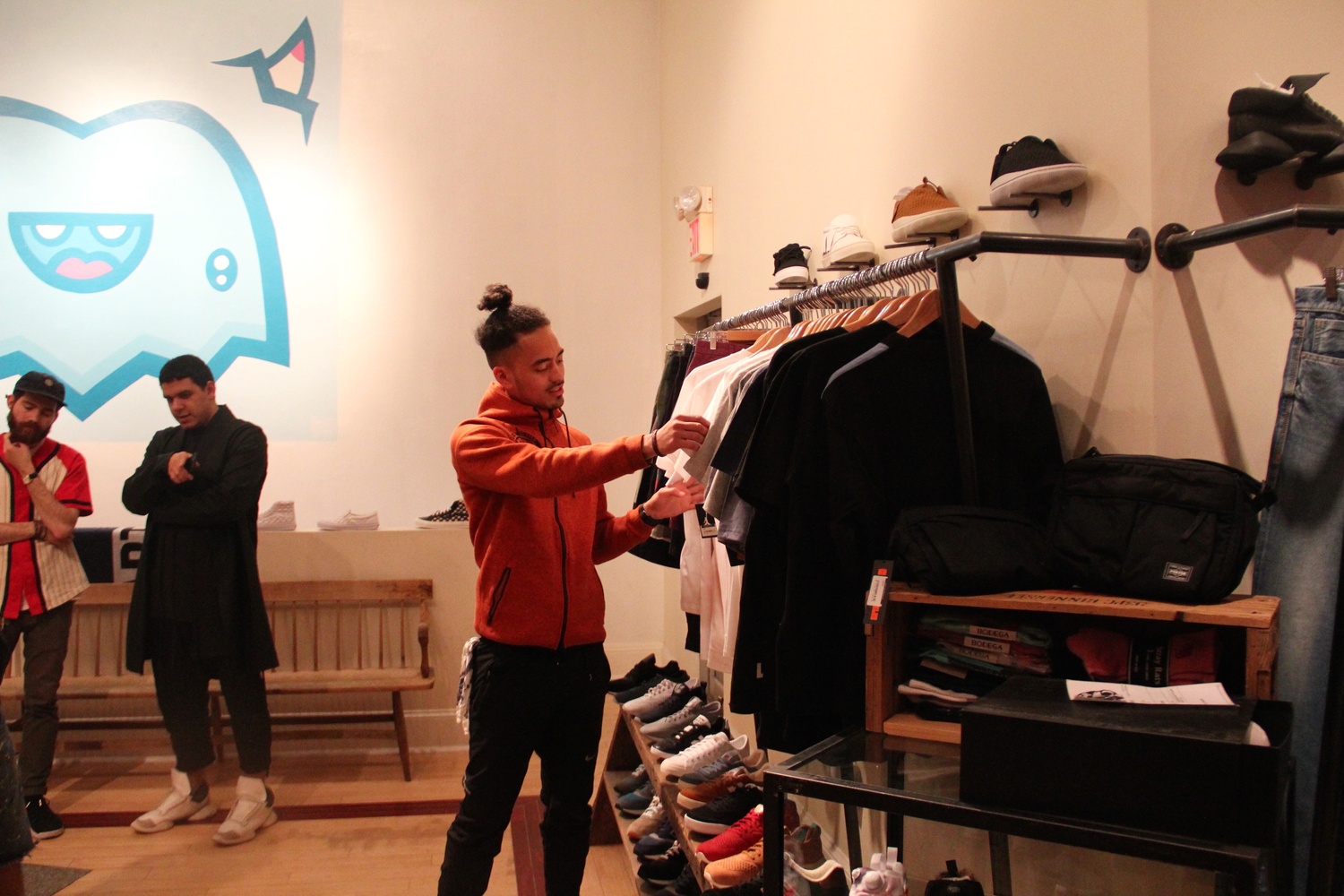 A customer looks through t-shirts. The store sells simple, modern clothes to suit Boston's young, hip demographic. The customers themselves wear the latest styles.