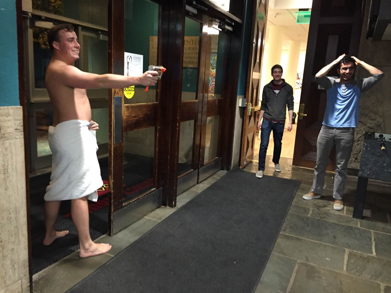 Wyatt M. Robertson '18 stands armed with a plastic toy gun and ready to drop his towel if need be while playing 'Assassins' in Quincy House.  According to game rules, participants can only "shoot" targets with the same attire. "So if someone comes at me, I just drop my towel and people can't shoot me," Robertson explained.
