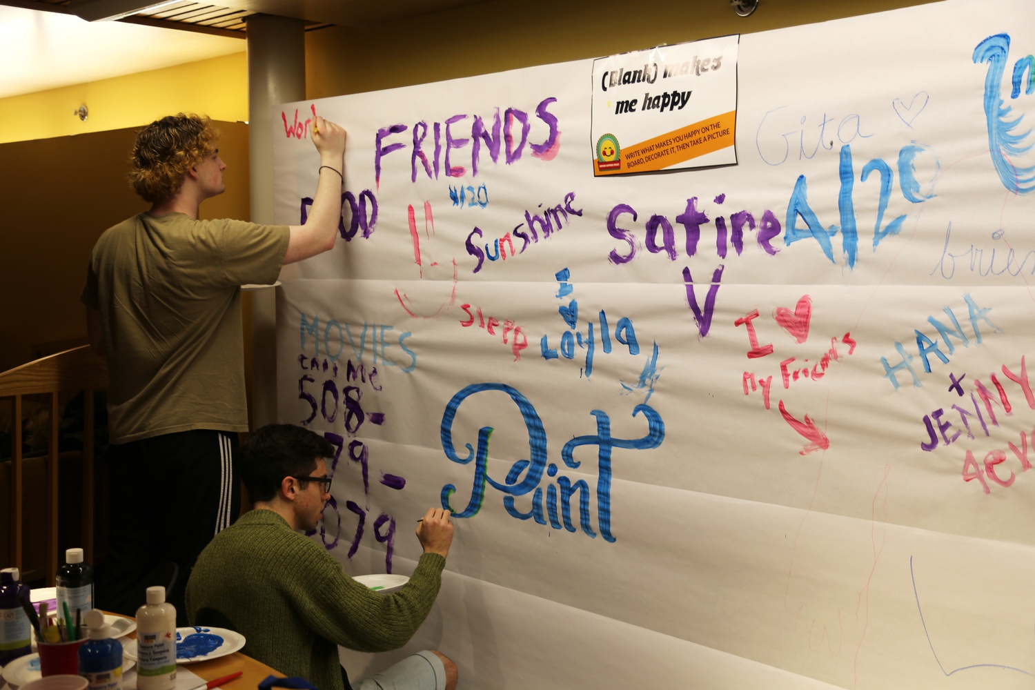 Students write what makes them happy during the Harvard Happiness Project study break Wednesday evening in Ticknor Lounge. 
