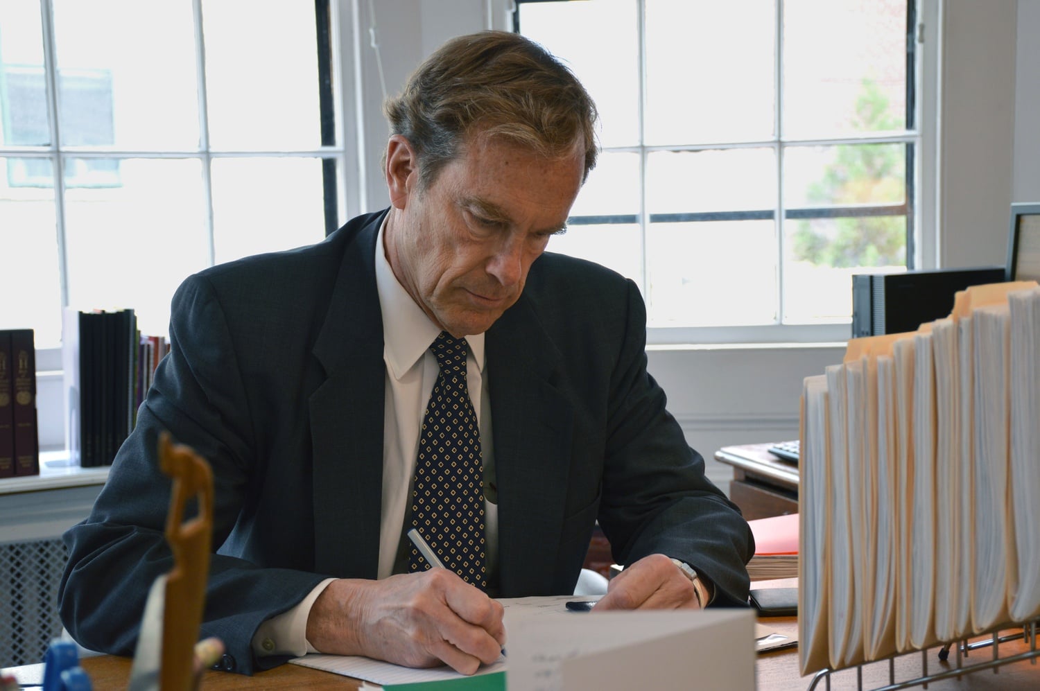 Interim Dean of Student Life Thomas A. Dingman '67 writes at his desk in the Freshman Dean's Office.