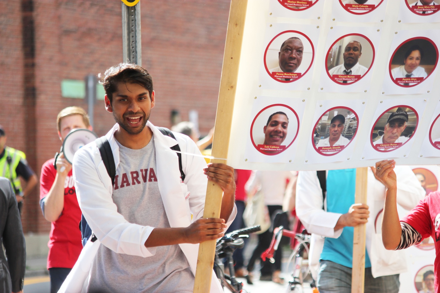 Sanjay Kishore, a student at the Medical School and a member of the school's Racial Justice Coalition, helps carry one of the posters displaying HUDS employees who are prepared to strike. "We came to medical school because we wanted to serve, but we can't do that if people don't have access to us," Kishore said during a panel prior to the march. 