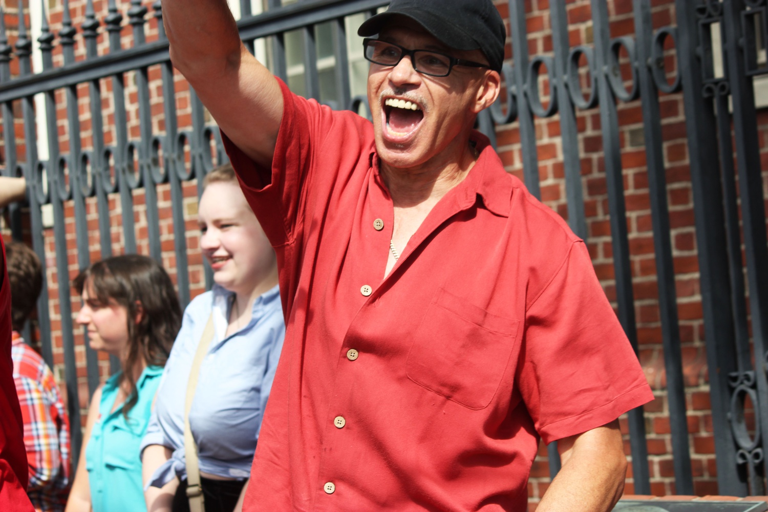 Gregory J. Lee, General Service HUDS worker in Quincy House, cheers as cars along Massachusetts Avenue honk at protesters during Wednesday’s HUDS rally