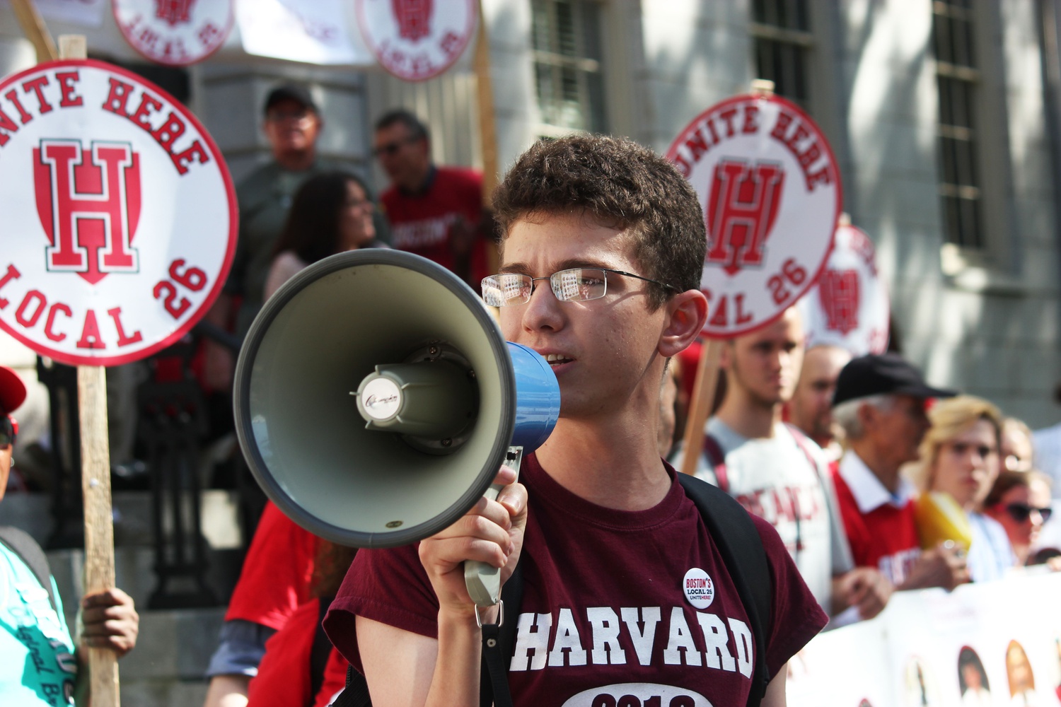 Gabe Hodgkin '18 stands with students and HUDS workers in front of the John Harvard statue during Wednesday's rally.