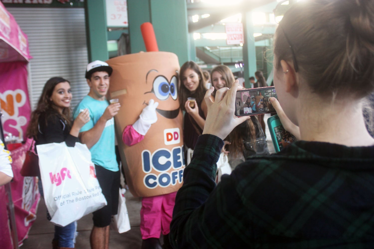 Students from various Boston area colleges have their photo taken with a Dunkin' Donuts mascot after receiving free coffee samples at CollegeFest 2016, a marketing event geared towards college students held annually at Fenway Park. 
