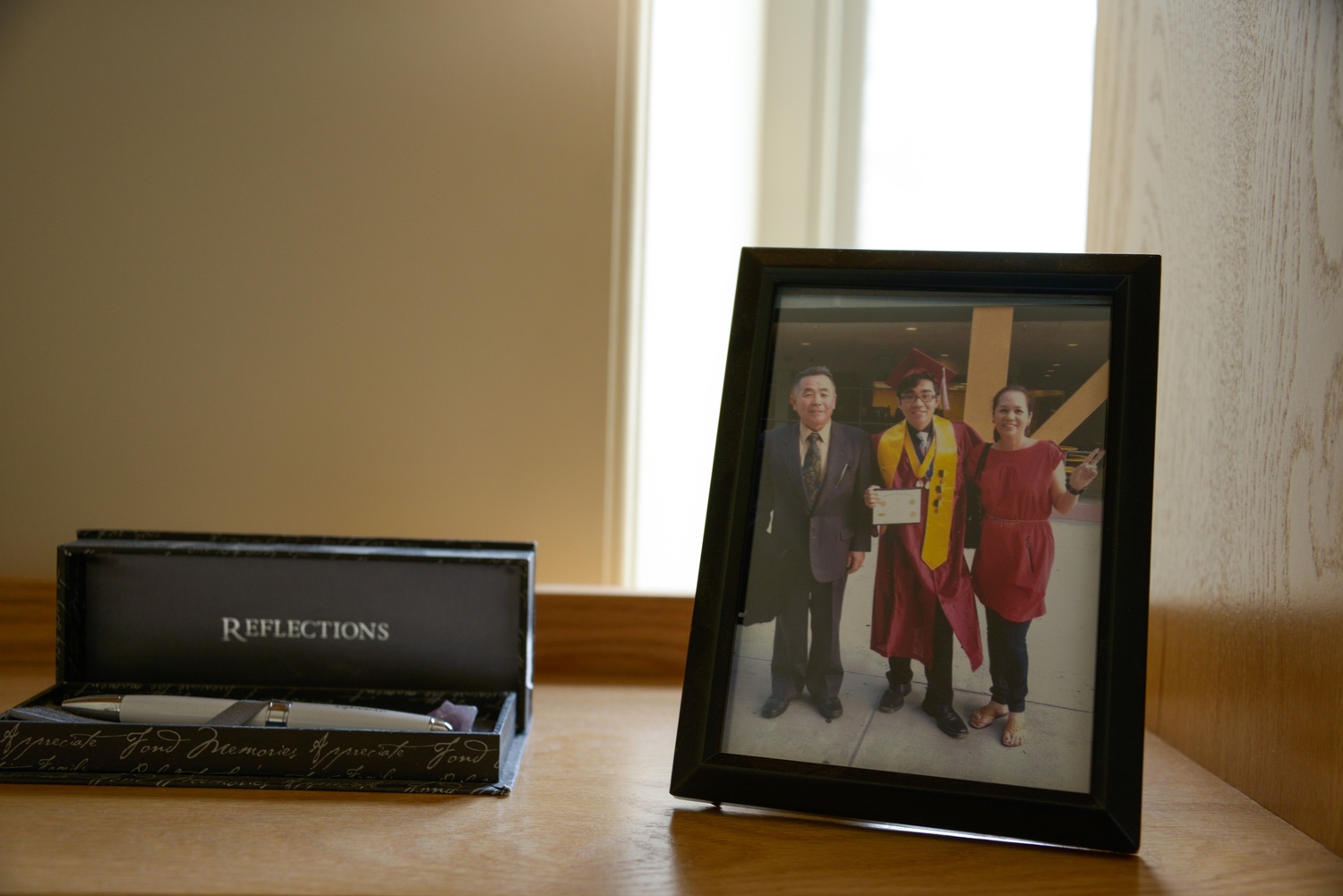 Daishi keeps memories of home, including a graduation photo with his parents and a pen, on his desk. 