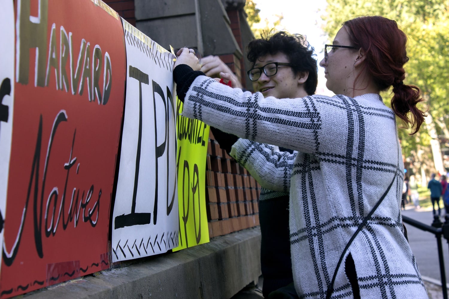 Kathleen L. Jackson of the African and African American Studies Department and Ian P. Maynor '17 tape signs at the Indigenous Peoples' Day celebration.