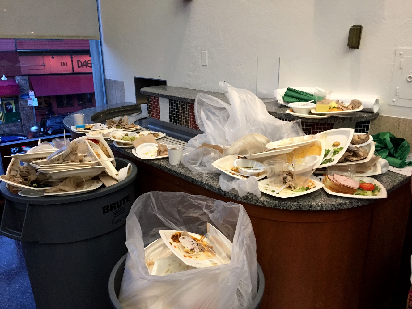 Disposable dishware and cutlery as well as food waste accumulates, over-filling trash receptacles during dinner in Quincy House dining hall.