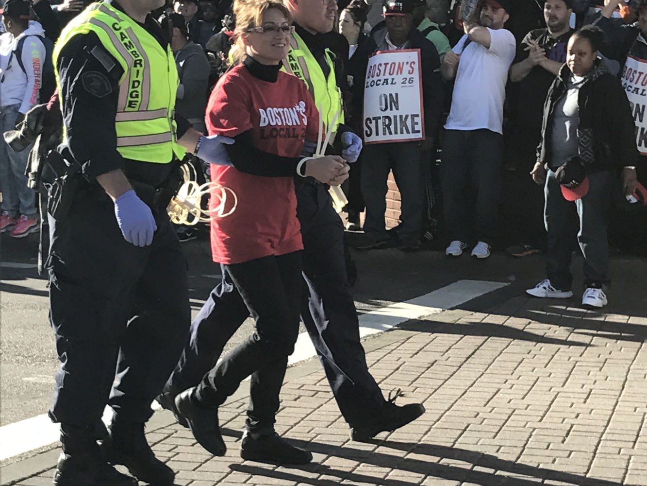 Dining services worker Anabela Pappas is escorted away in handcuffs by a Cambridge Police officer Friday. 