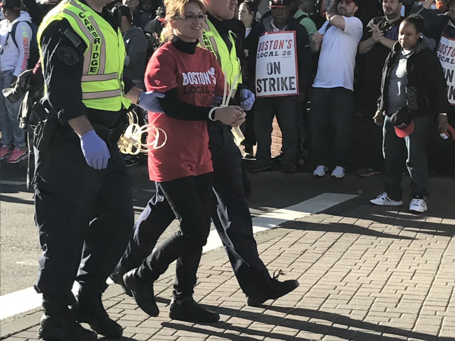 Dining services worker Anabela Pappas is escorted away in handcuffs by a Cambridge Police officer Friday. 