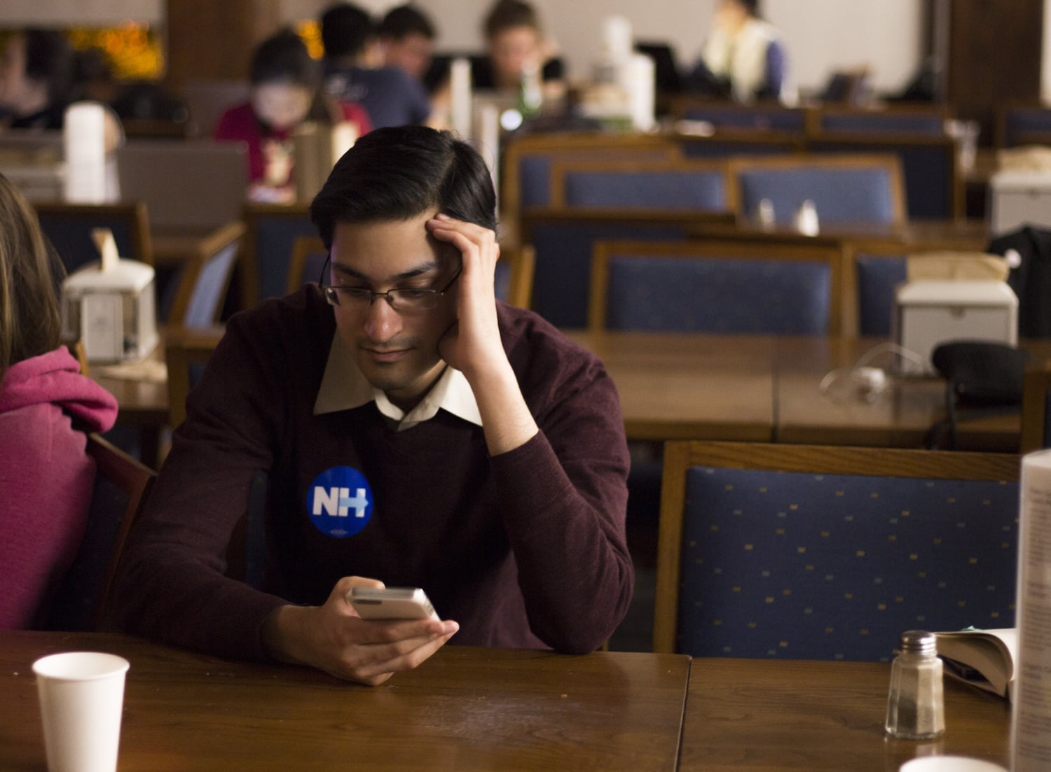 Rush Doshi, donning a Hillary Clinton sticker, checks his phone in despair shortly after the announcement of Donald Trump winning Ohio. Doshi attended the watch party in Quincy dining hall Tuesday night.