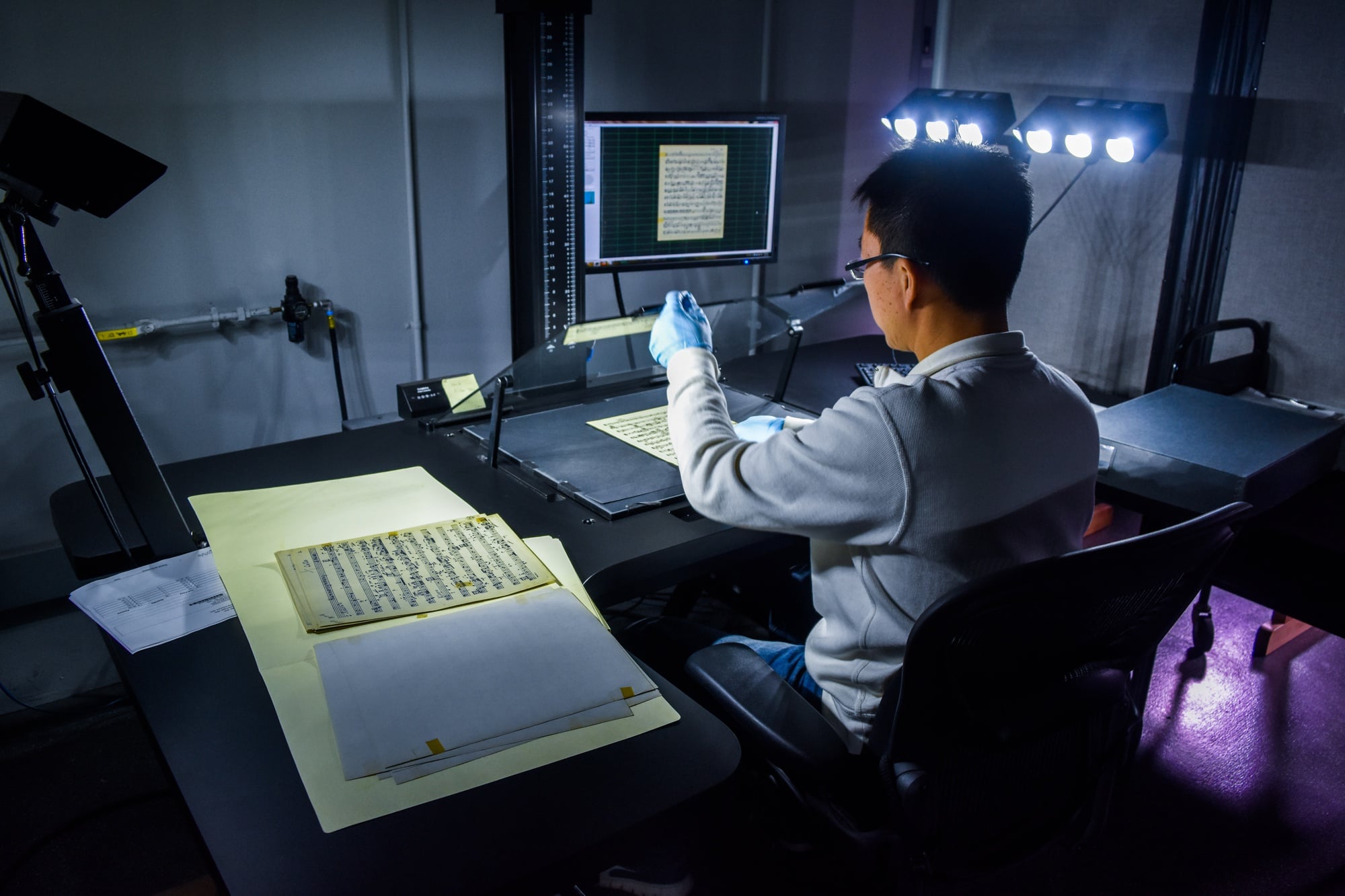 Camera operator Ying B. Li works to scan physical sheets of music into Harvard's digital archives. 