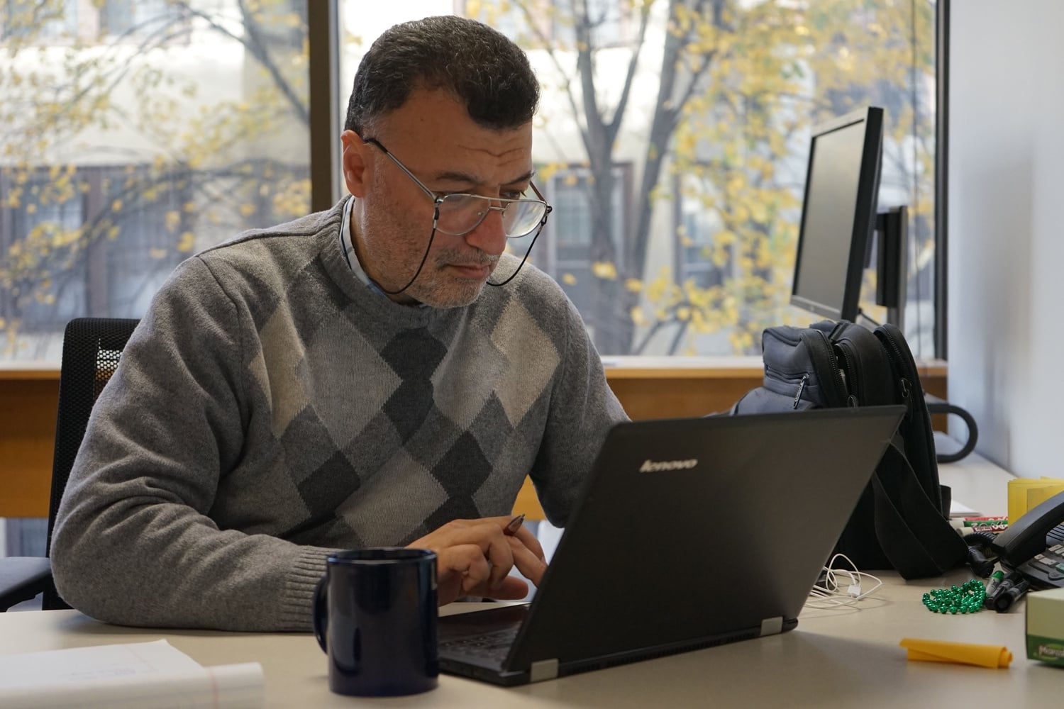 Mahmoud Hariri working at his desk in the Harvard Humanitarian Initiative office as a current Scholars at Risk fellow.