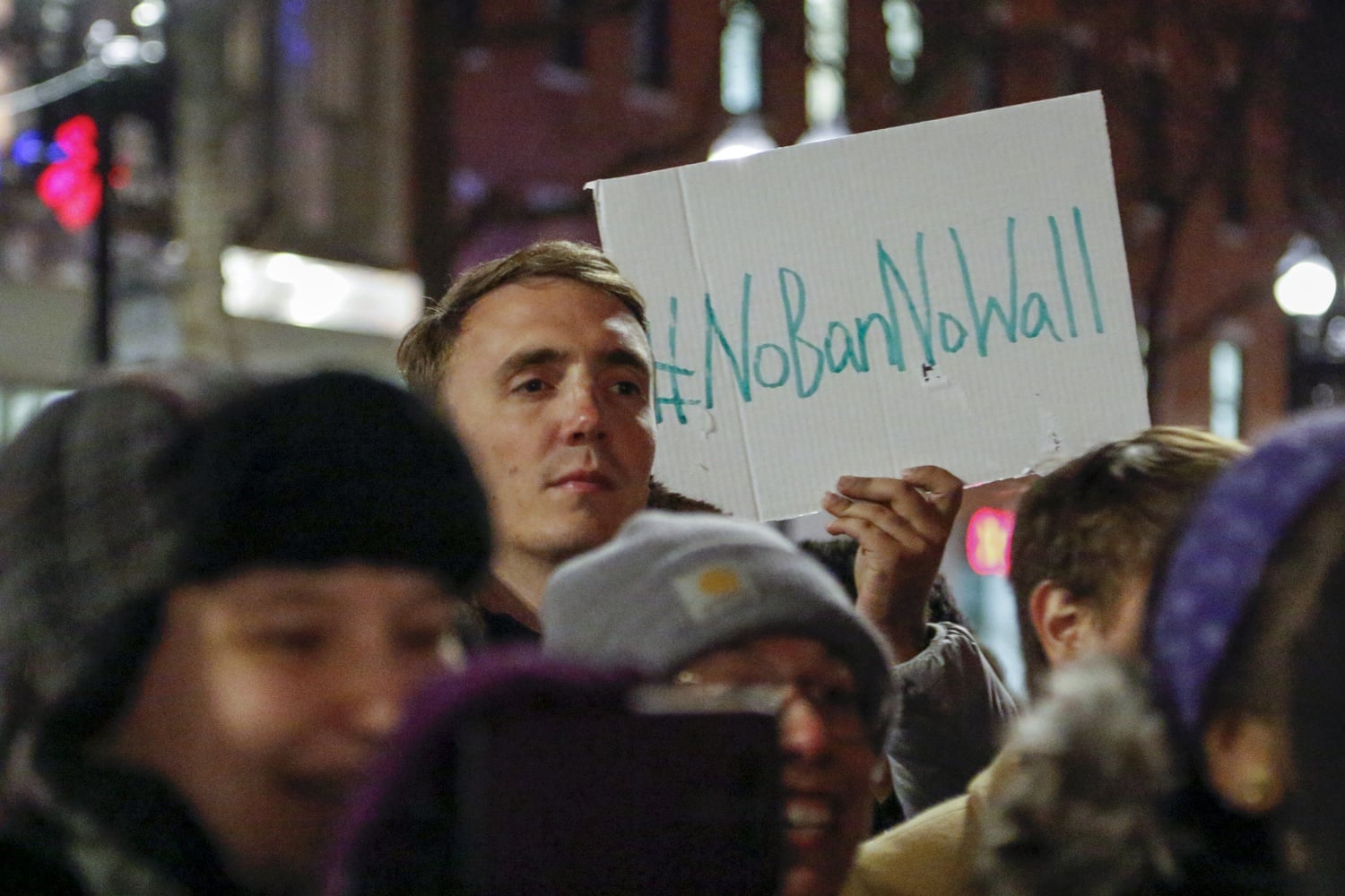 A demonstrator holds a sign reading "#NoBanNoWall" during a rally in Harvard Square opposing recent immigration policy changes.