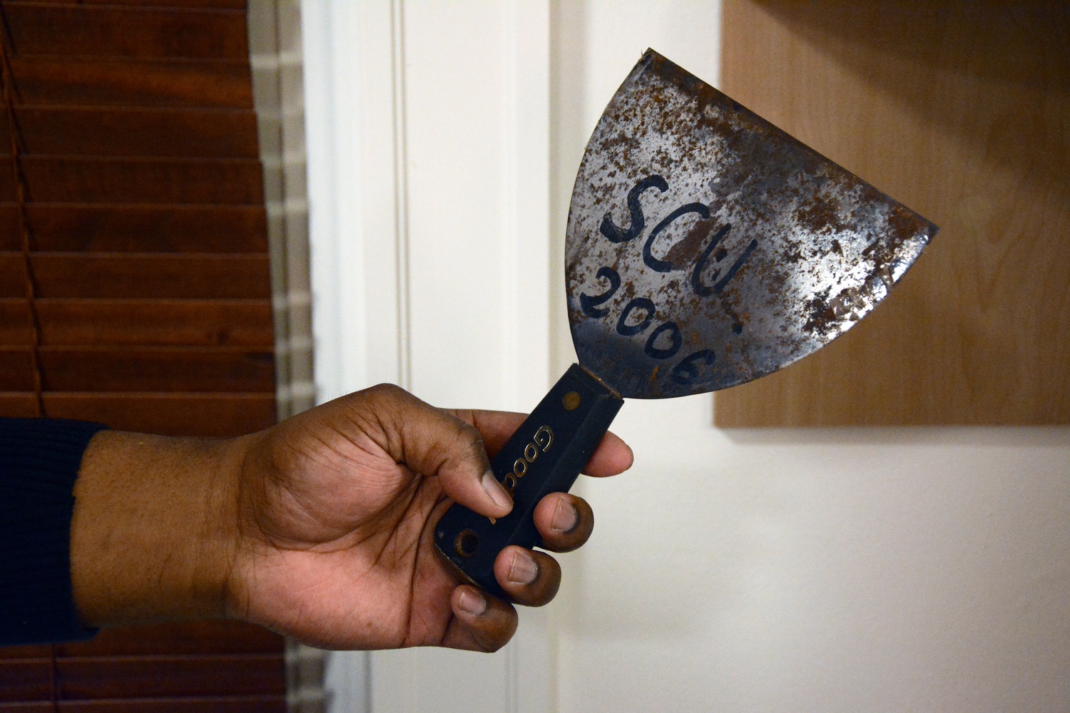 Sheehan Scarborough holds a putty knife he used when working for Dorm Crew throughout his college career. Scarborough describes Dorm Crew as one of the most significant parts of his college experience.