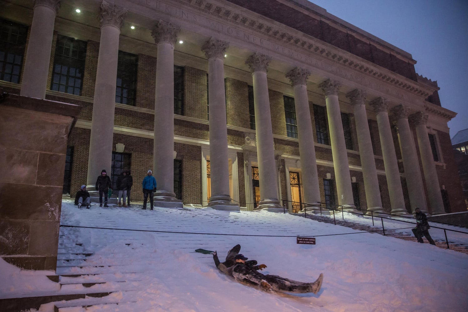 After a day of classes during a storm that brought in over a foot of snow, students brought lunch trays to slide down the steps of Widener Library. While some classes were cancelled by professors, the College was still officially open.