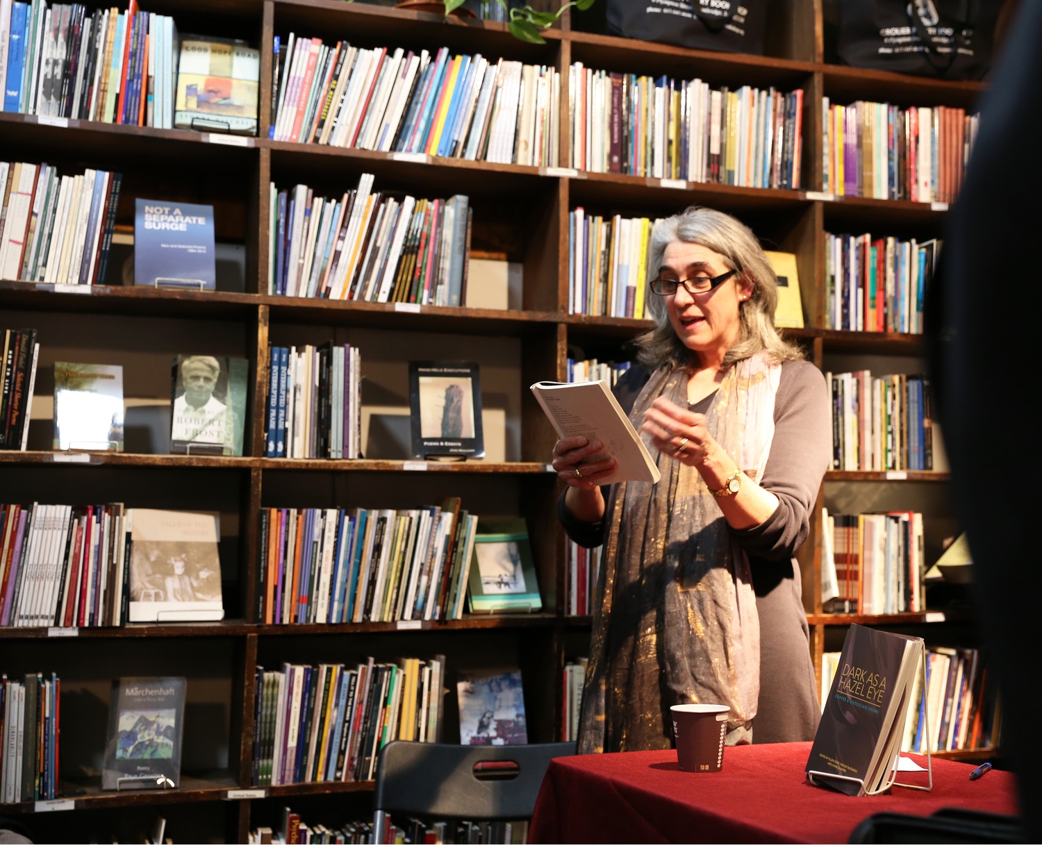 Therese Sellers, a contributing poet to the collection “Dark as a Hazel Eye: Coffee and Chocolate Poems”, reads one of her poems aloud in the Grolier Poetry Bookshop. 