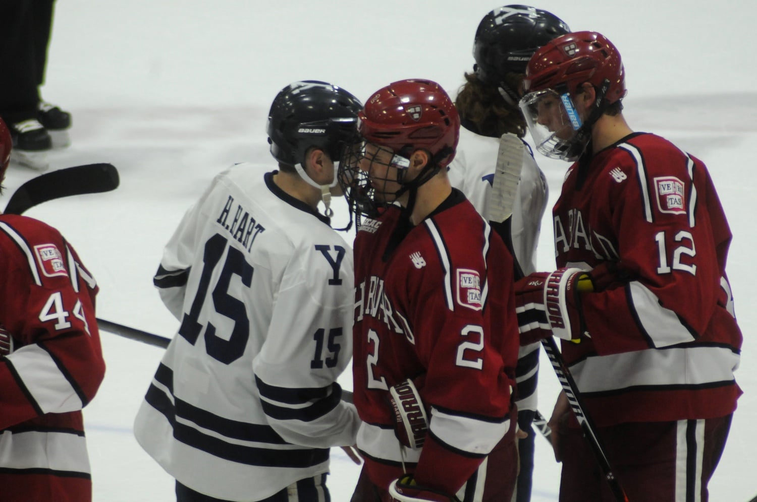 Senior forward Tyler Moy (2) and freshman defenseman John Marino (12) shake hands with members of the Bulldogs after Friday's game. The two combined for three of the Crimson's four goals.