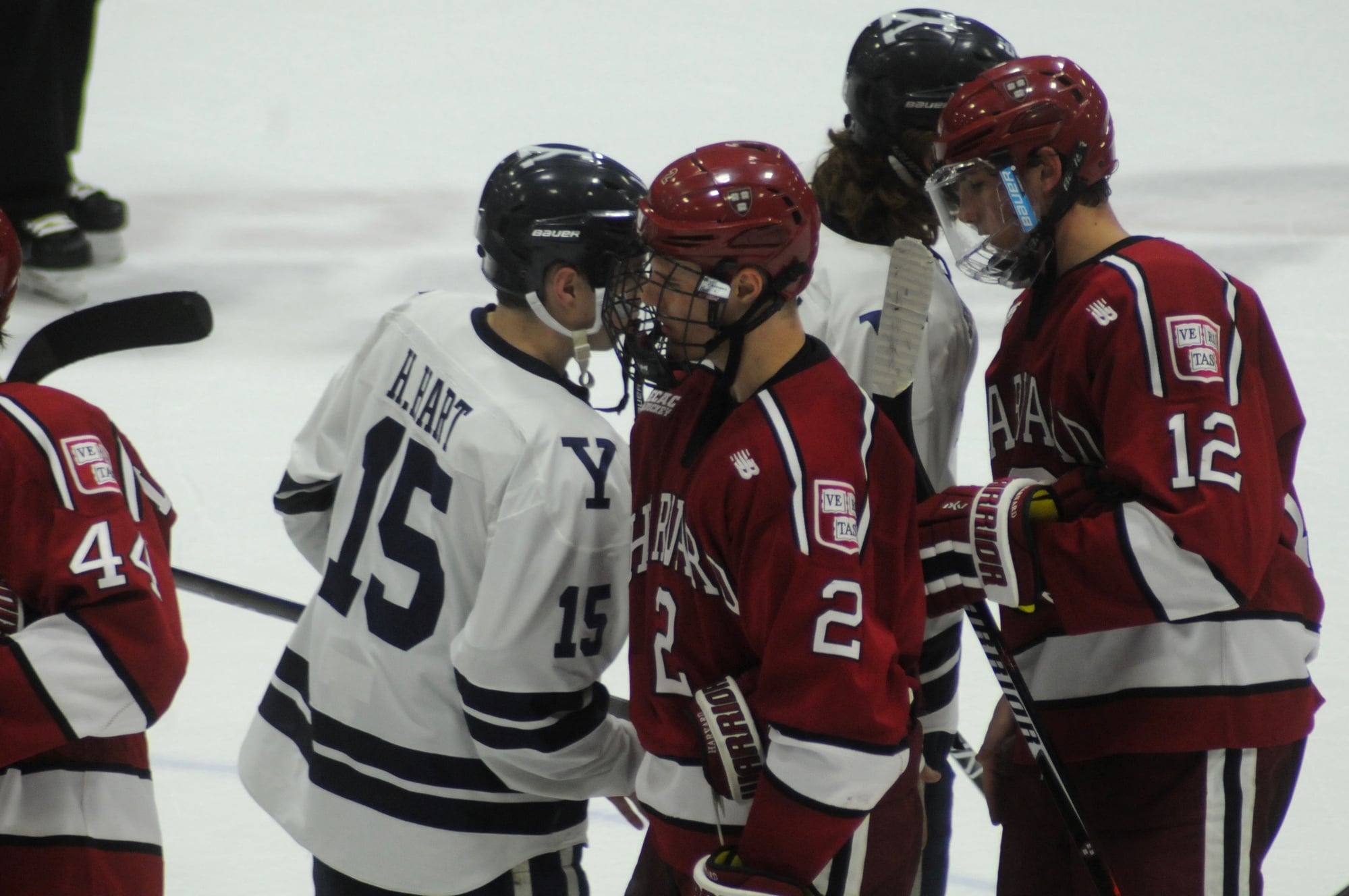 Senior forward Tyler Moy (2) and freshman defenseman John Marino (12) shake hands with members of the Bulldogs after Friday's game. The two combined for three of the Crimson's four goals.