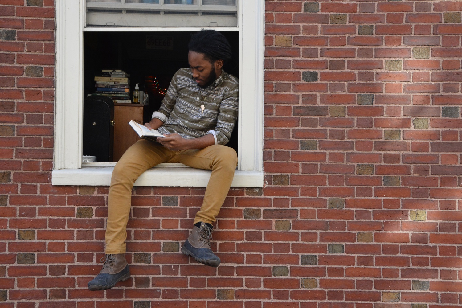 Julius U. Wade ’20 sits on his windowsill as he reads a book. 