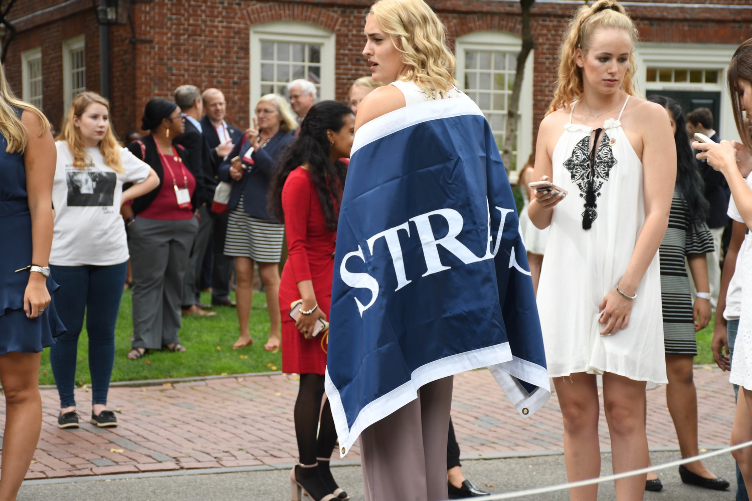 Kate L. Wallace '21 wraps herself in the Straus Hall banner while waiting for Convocation in the Yard on Tuesday.