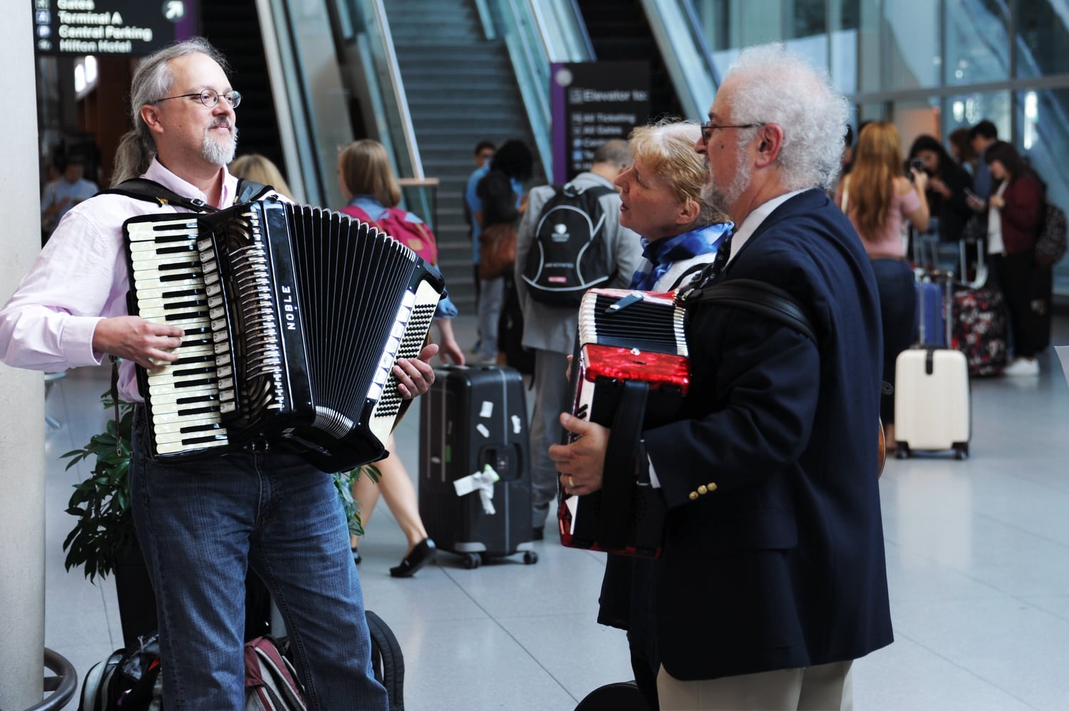 Professor Thomas M. Michel ’77, right, plays the accordion as he and others await the arrival of Iranian scientist Seyed S. S. Saravi at Logan International Airport Wednesday afternoon. 