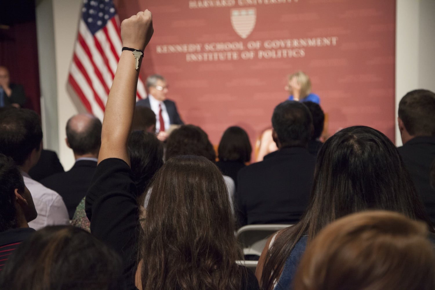 A student raises her fist in the air in an act of silent protest against Secretary of Education Betsy DeVos Thursday evening. Hundreds of students and locals turned out to protest DeVos' speech at the Harvard Kennedy School.