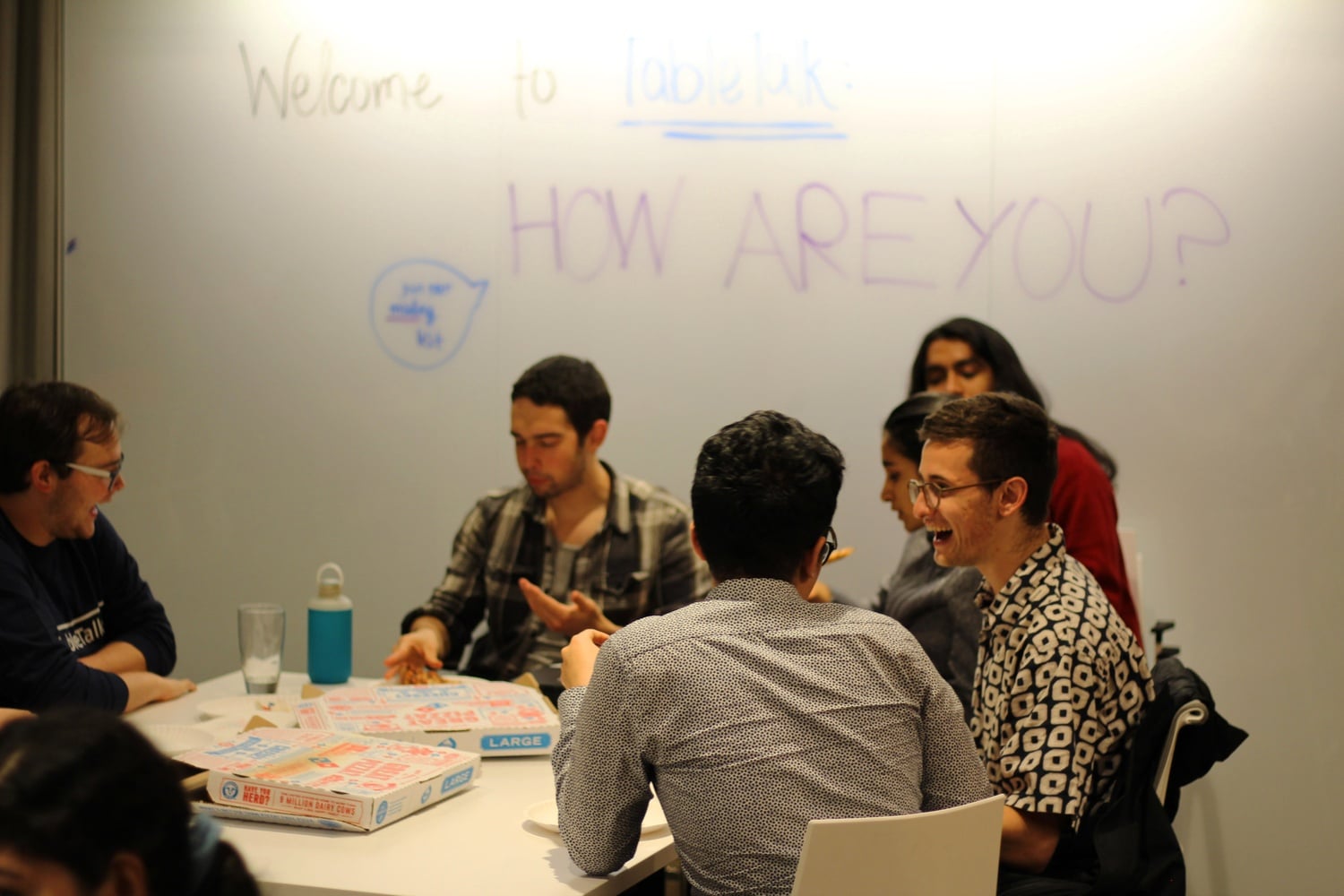 Students gather around pizza to discuss the significance of the question “how are you?” at TableTalk Harvard’s first event Monday night.