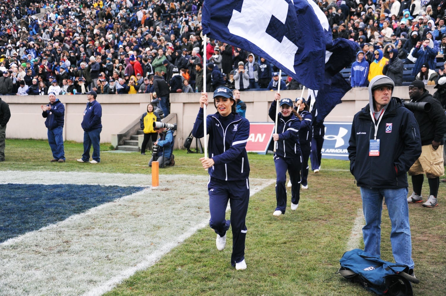 Yale's cheerleaders run along the sidelines with flags.