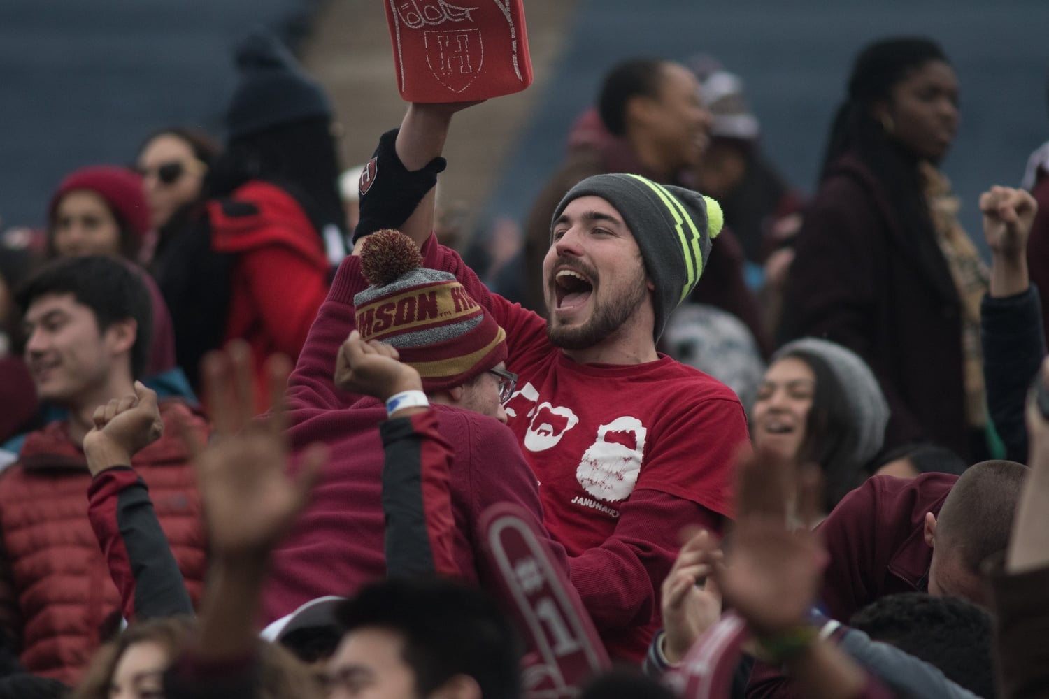 Two Harvard fans celebrate in the crowd.