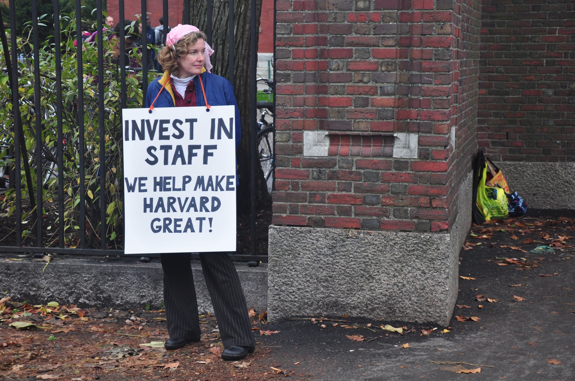 A member of the Harvard Union of Clerical and Technical Workers (HUCTW) wears a sign asking Harvard to invest in its staff in November of 2012.