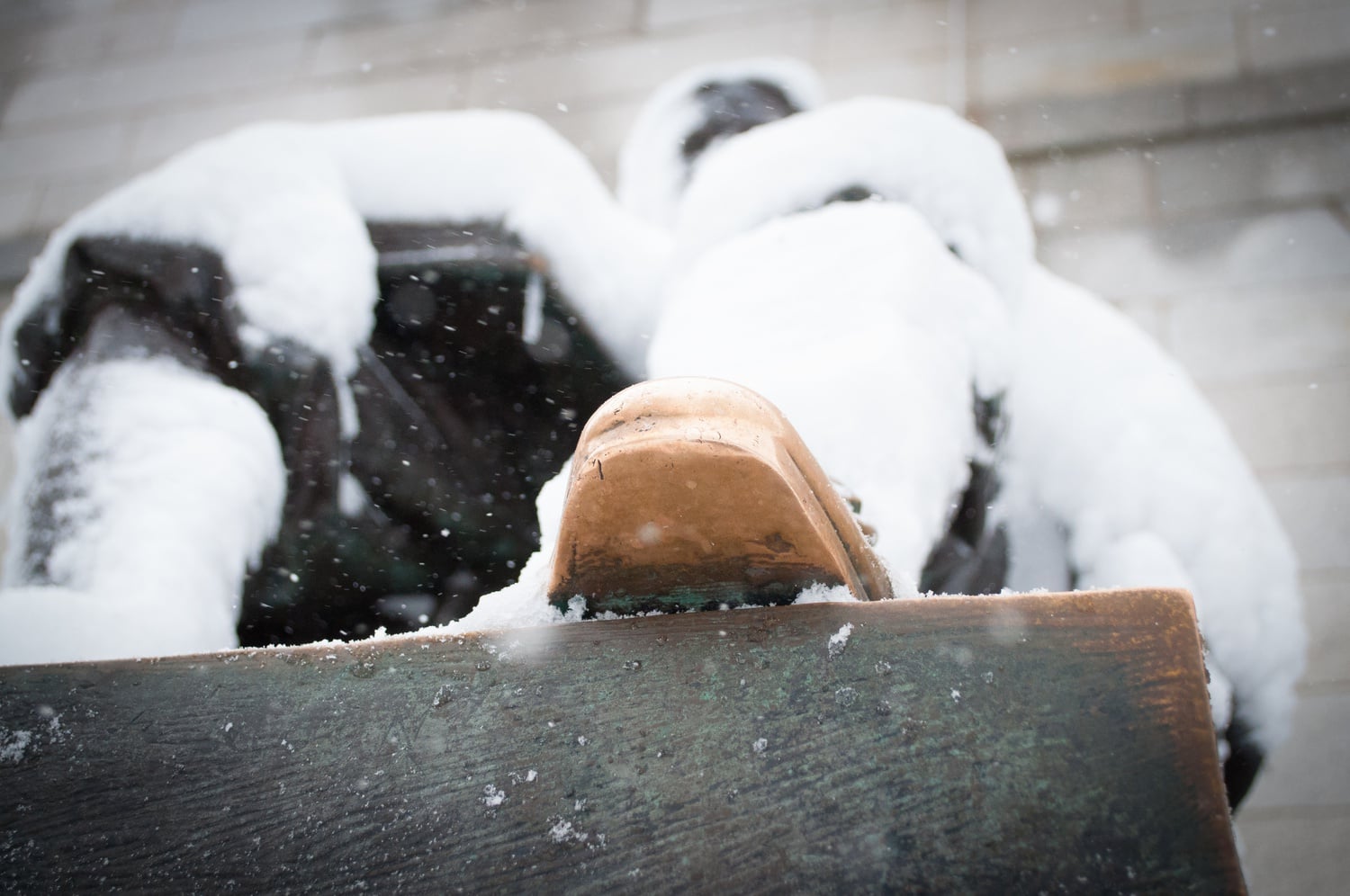 Snow covers the infamous John Harvard statue in the Yard outside of University Hall.