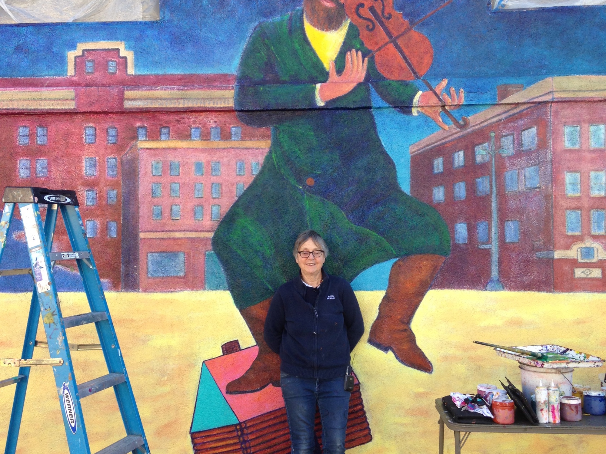 Christina Schlesinger is pictured standing in front of her mural titled “Chagall Returns to Venice Beach” in 2016. 