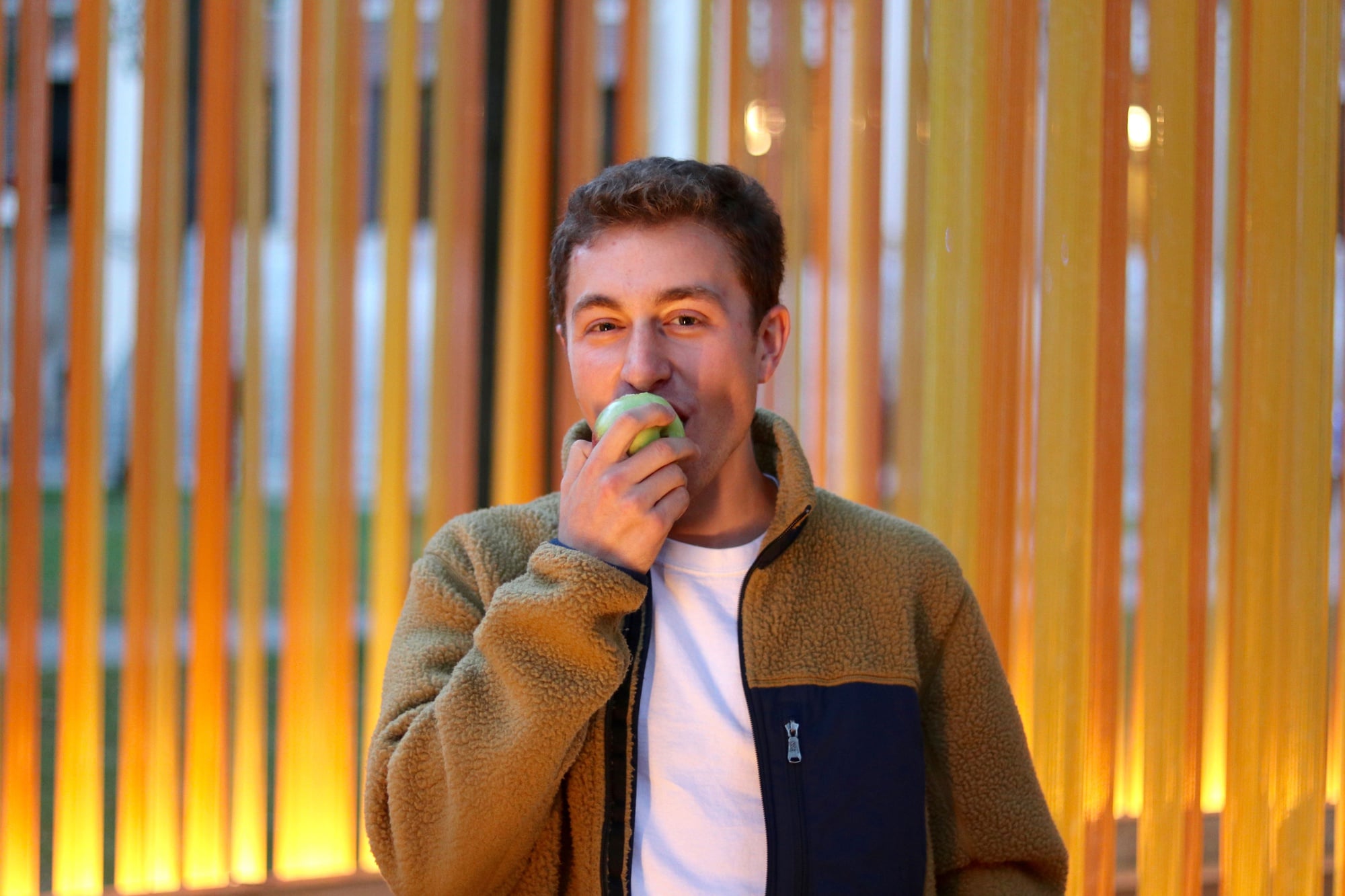 Austin B. Weber '19 snacks on an apple in Harvard Yard.