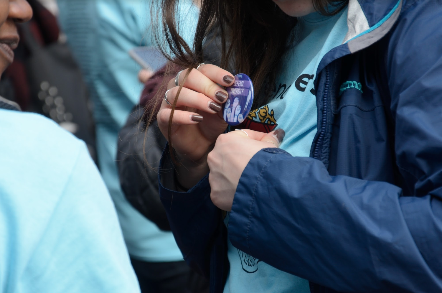 A protester pins a button to her shirt at a pro-Harvard and pro-affirmative action rally held Sunday afternoon in the Square.