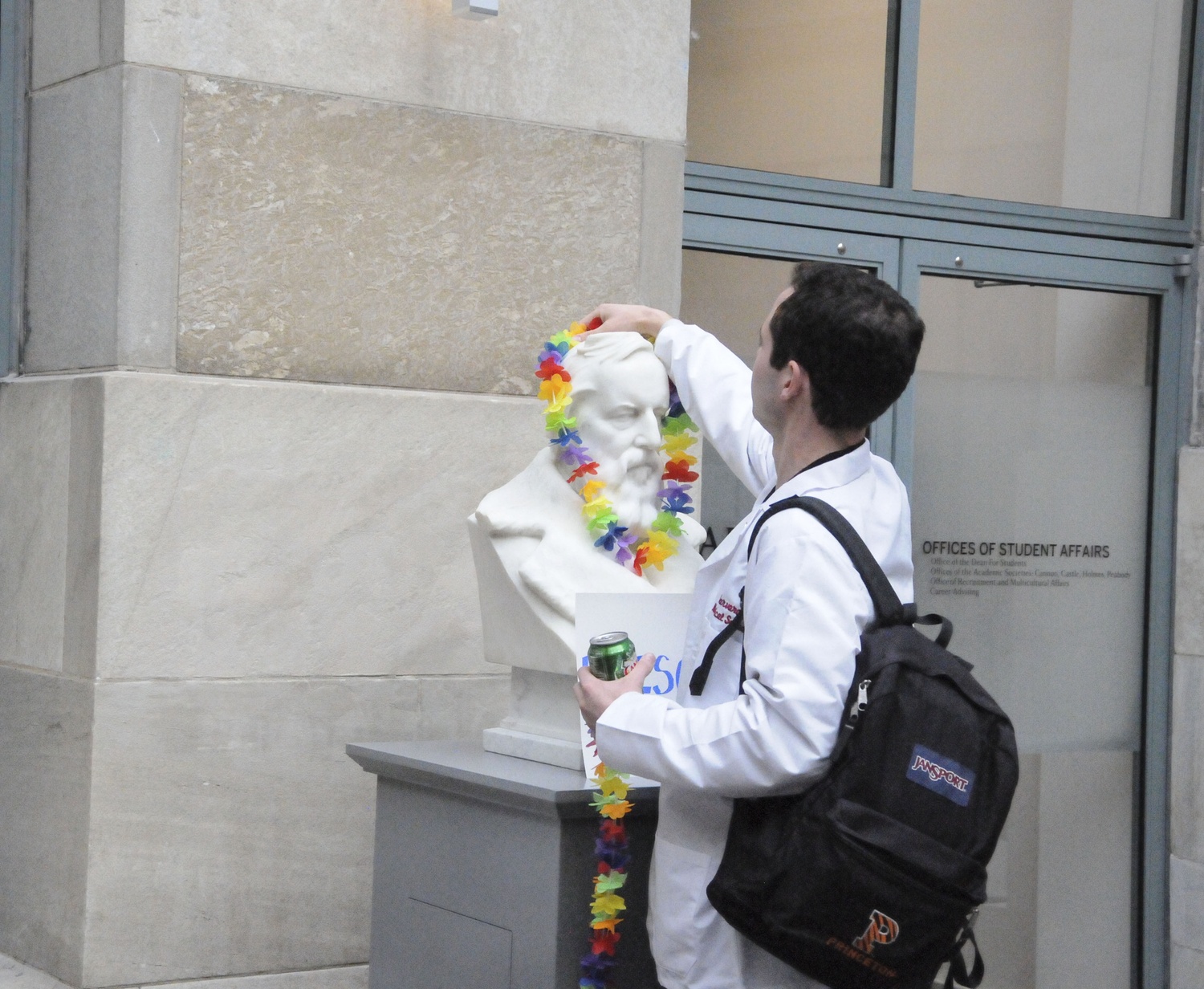A Harvard Medical School student places a rainbow lei over a bust during a protest advocating for transgender rights at the Medical School on Thursday.