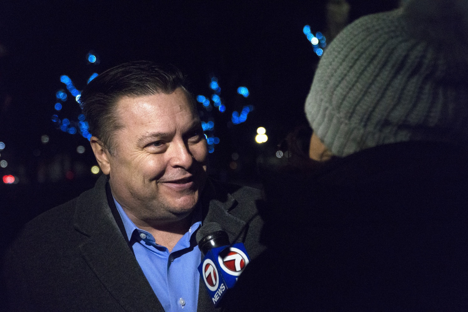 Cambridge mayor Marc C. McGovern speaks to a reporter at the menorah lighting.