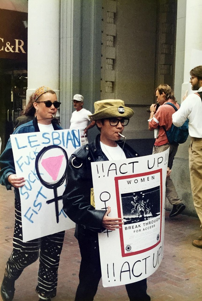 At the International AIDS conference, two activists whistle while marching down the street, holding homemade posters.