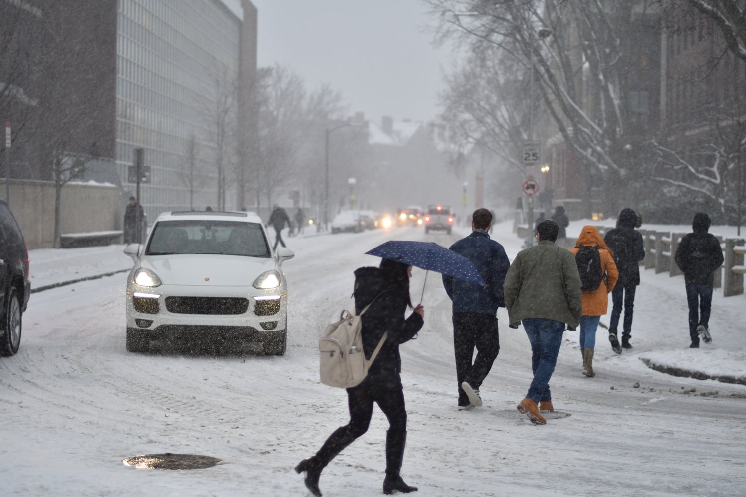 Students cross the street in front of Lowell Lecture Hall to attend classes, which continued despite Sunday night's heavy snowfall.
