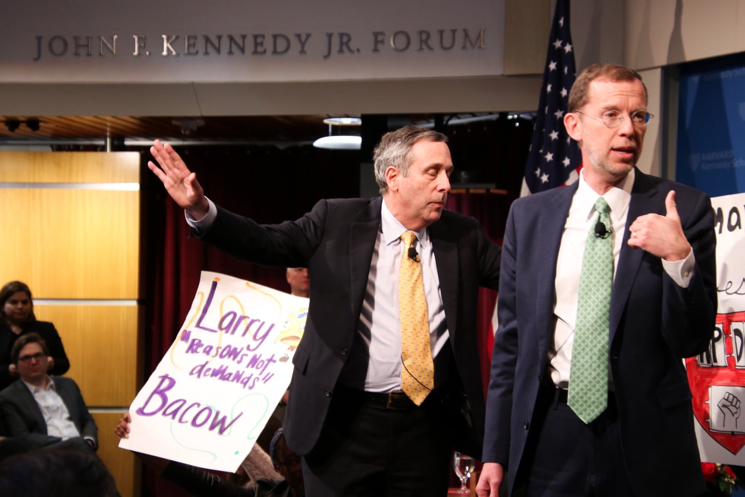 University President Lawrence S. Bacow attempts to quiet protestors before exiting the John F. Kennedy Jr. Forum.