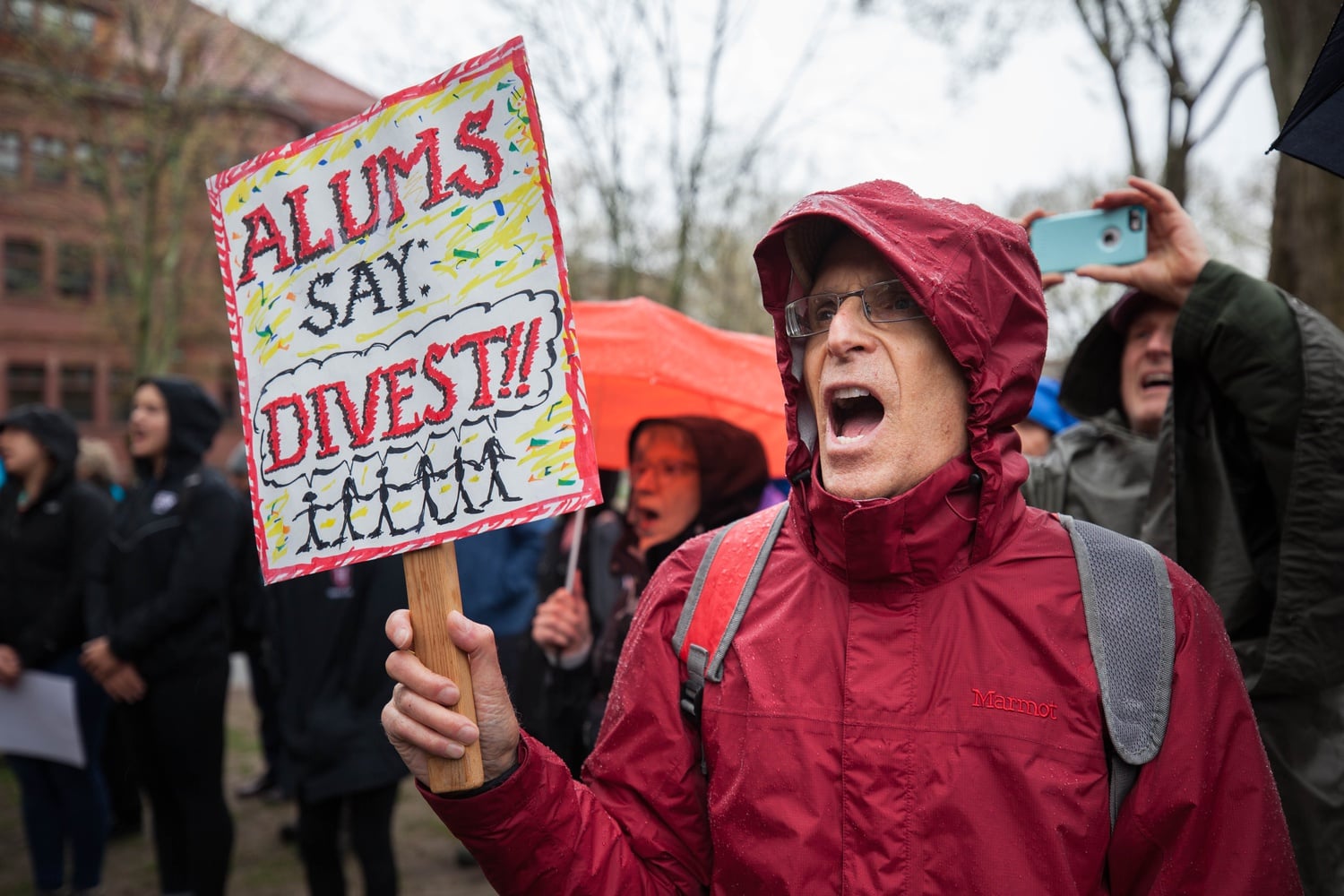 A Harvard alum holds a sign proclaiming his support for Divest Harvard, an undergraduate-led effort to push the University to divest funds from fossil fuels.