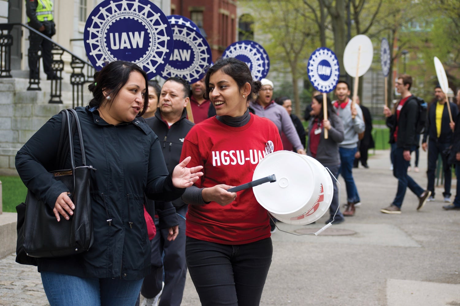 Niharika N. Singh chats to another participant as they march in the Union March in front of the John Harvard statue. Singh is on the bargaining committee for the graduate students.